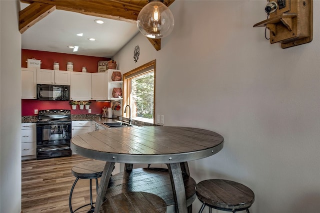 kitchen with a sink, recessed lighting, white cabinetry, wood finished floors, and black appliances