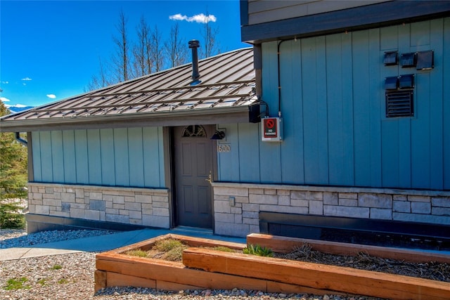 view of exterior entry with stone siding and metal roof