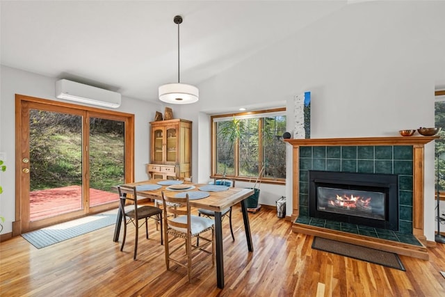 663 Amethyst Dr, Steamboat Springs, CO 80487 - dining room with a wall mounted AC, wood finished floors, a tiled fireplace, baseboards, and lofted ceiling