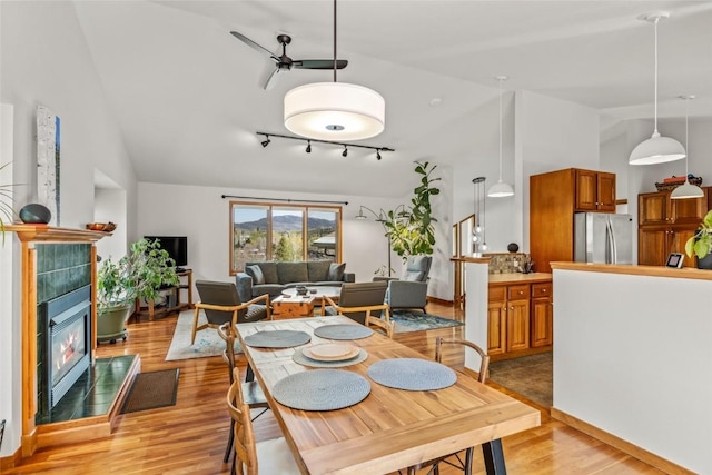 663 Amethyst Dr, Steamboat Springs, CO 80487 - dining area featuring light wood-style flooring, ceiling fan, a tile fireplace, rail lighting, and high vaulted ceiling