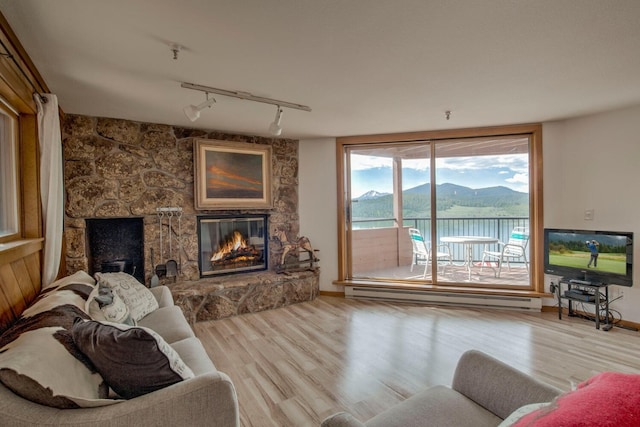 188 E Ln Bonte St Unit 327, Dillon, CO 80435 - living room with a baseboard heating unit, a stone fireplace, track lighting, and wood finished floors