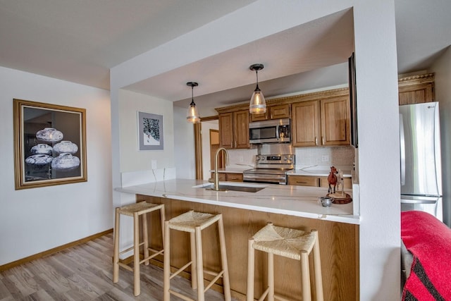 188 E Ln Bonte St Unit 327, Dillon, CO 80435 - kitchen with appliances with stainless steel finishes, a peninsula, brown cabinets, a kitchen breakfast bar, and pendant lighting