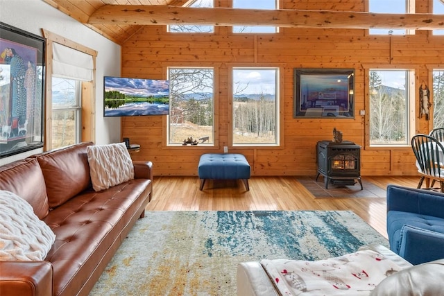 living room featuring a wood stove, wood walls, hardwood / wood-style floors, wooden ceiling, and vaulted ceiling