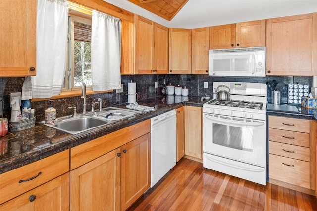 kitchen with backsplash, wood finished floors, a sink, tile counters, and white appliances