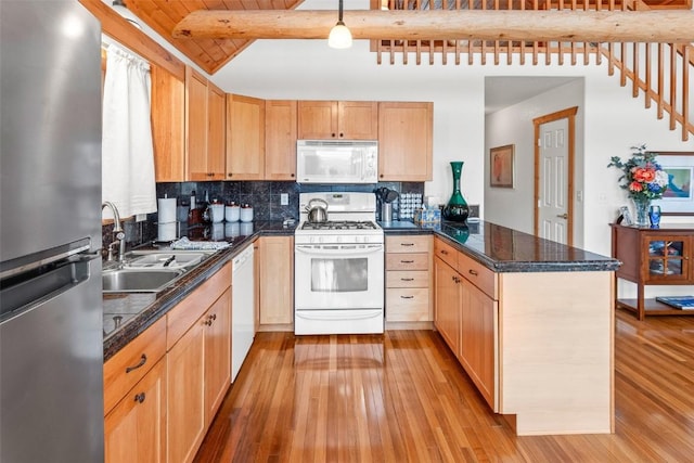 kitchen with a sink, light wood-style floors, white appliances, a peninsula, and beamed ceiling