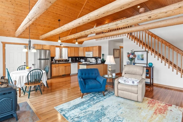living area with a wood stove, wood ceiling, light wood finished floors, and beamed ceiling