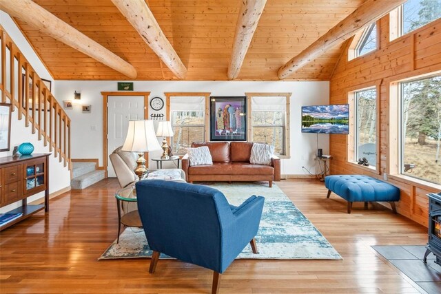 living room featuring a wood stove, wooden ceiling, baseboards, vaulted ceiling with beams, and stairs