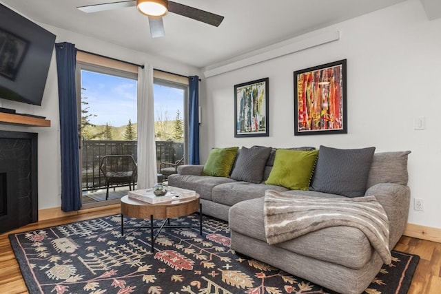 living area featuring wood finished floors, ceiling fan, and a fireplace