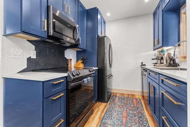 kitchen featuring stainless steel appliances, blue cabinetry, backsplash, light countertops, and recessed lighting