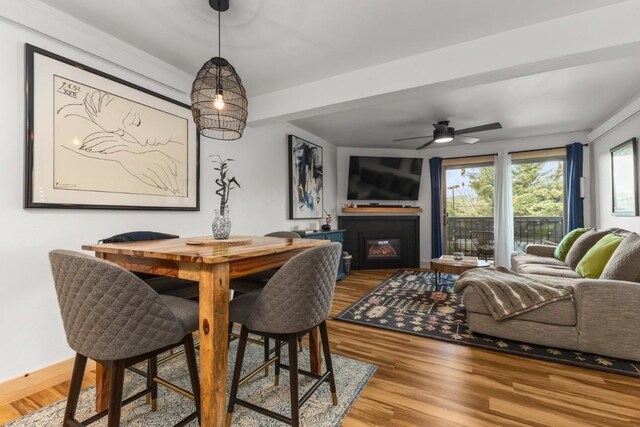 dining room with wood finished floors, ceiling fan, and a glass covered fireplace