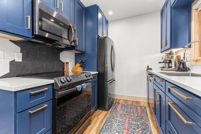 kitchen with appliances with stainless steel finishes, blue cabinets, a sink, backsplash, and recessed lighting