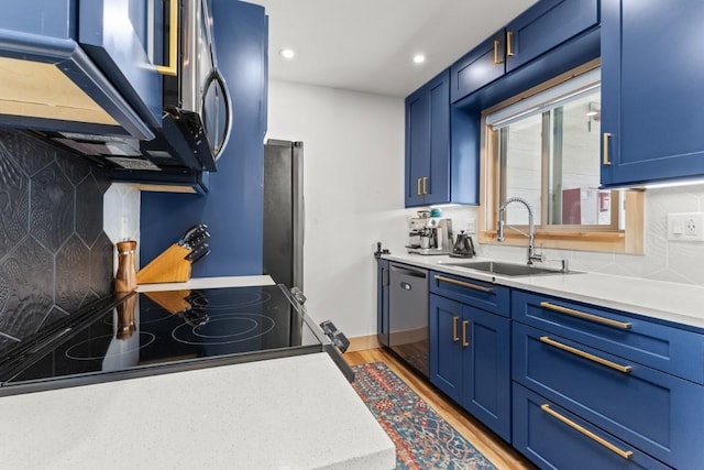 kitchen featuring a sink, blue cabinetry, backsplash, light countertops, and recessed lighting