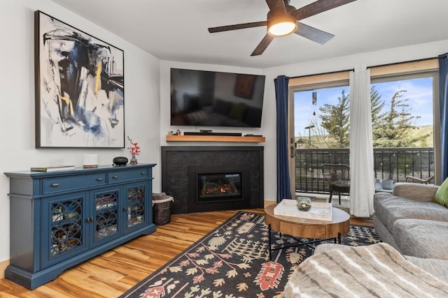 living room with wood finished floors, ceiling fan, and a glass covered fireplace