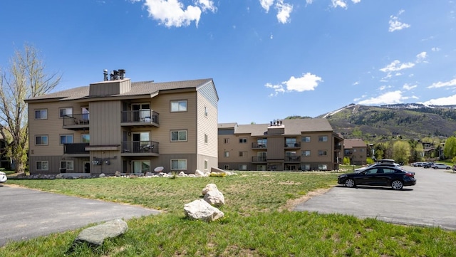 view of property with a mountain view and uncovered parking