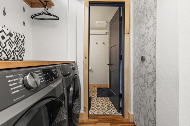 clothes washing area featuring washer and clothes dryer and wood finished floors