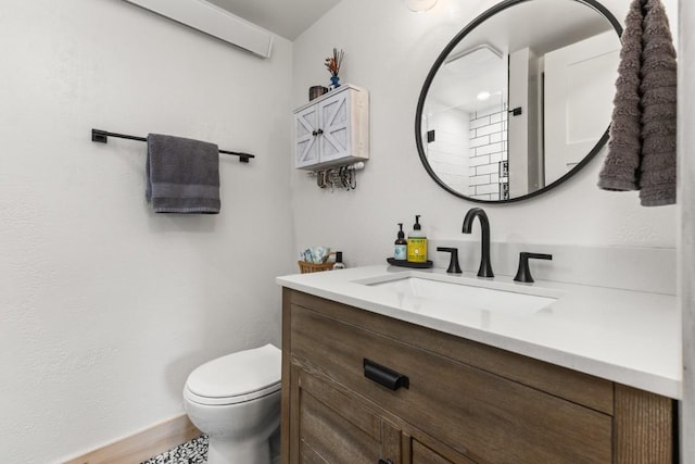 bathroom with toilet, vanity, baseboards, and wood finished floors