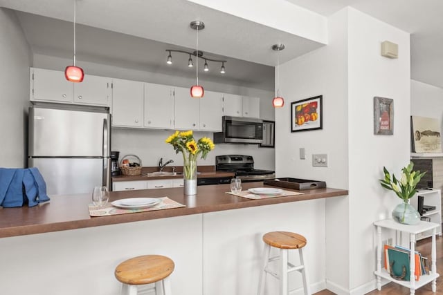 3 Cedar Ct Unit 3, Steamboat Springs, CO 80487 - kitchen with appliances with stainless steel finishes, white cabinets, a peninsula, and a breakfast bar