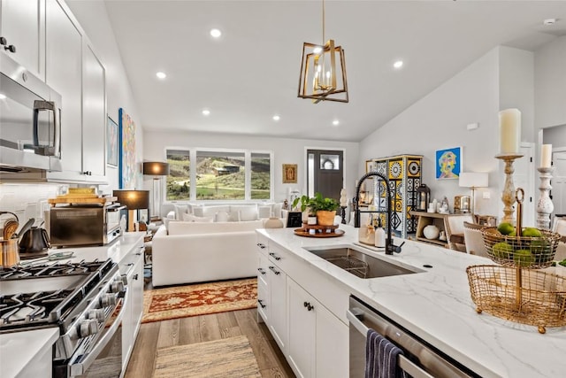 23430 Postrider Trl, Oak Creek, CO 80467 - kitchen with a sink, stainless steel appliances, light wood finished floors, open floor plan, and light stone counters