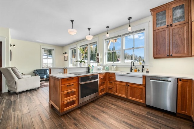 25640 6th Ave, Hahns Peak, CO 80428 - kitchen featuring brown cabinets, stainless steel appliances, a sink, dark wood-type flooring, and a peninsula