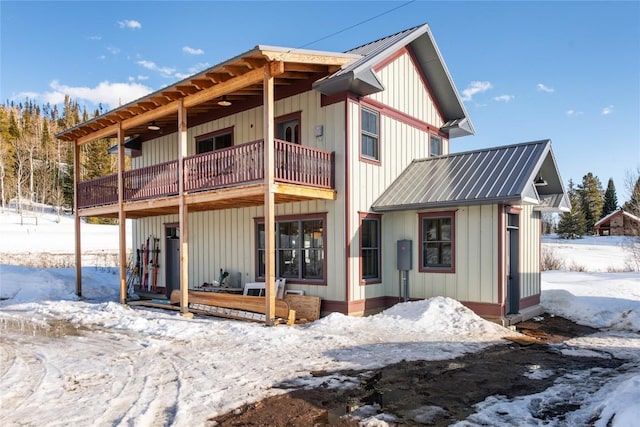 25640 6th Ave, Hahns Peak, CO 80428 - snow covered rear of property with board and batten siding, a balcony, and metal roof
