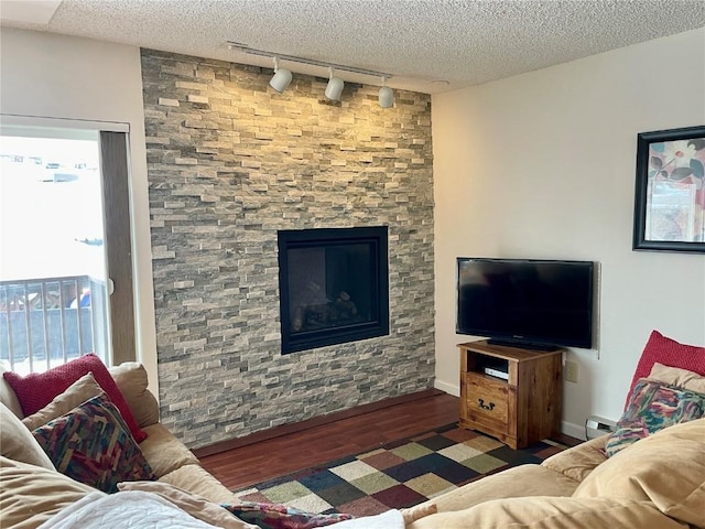 living area with a baseboard heating unit, a textured ceiling, wood finished floors, and rail lighting