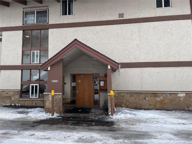 snow covered property entrance featuring stucco siding