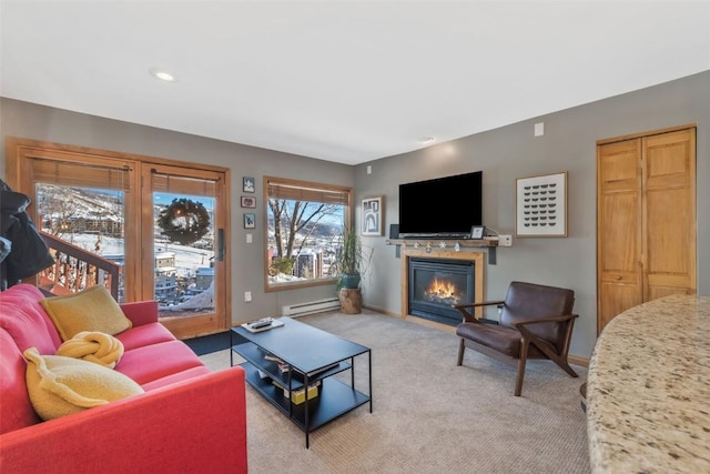 living room with a baseboard radiator, a glass covered fireplace, baseboards, and light carpet