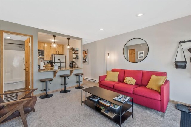 living area with a baseboard heating unit, light carpet, recessed lighting, and baseboards