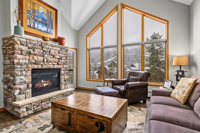 23110 US Highway 6 Unit 5044, Keystone, CO 80435 - living area featuring a stone fireplace, wood finished floors, lofted ceiling, a baseboard heating unit, and baseboards