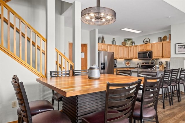23110 US Highway 6 Unit 5044, Keystone, CO 80435 - kitchen with appliances with stainless steel finishes, decorative backsplash, wood finished floors, a kitchen bar, and a peninsula