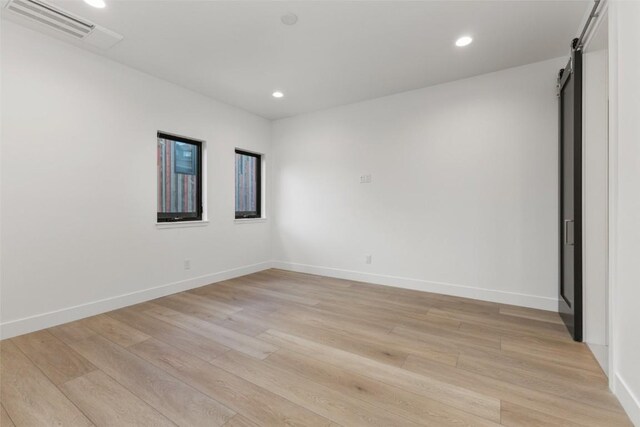 spare room featuring a barn door and light hardwood / wood-style floors