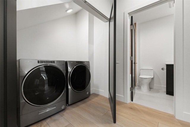 laundry area featuring separate washer and dryer and light hardwood / wood-style flooring