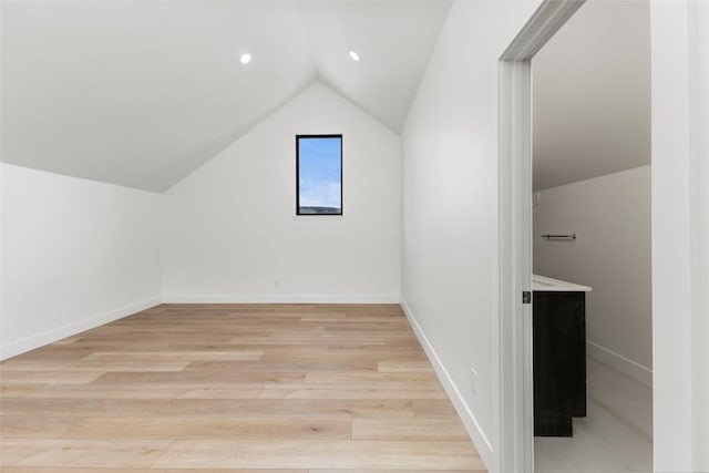 additional living space with light hardwood / wood-style floors and lofted ceiling