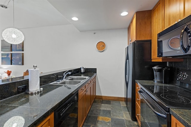 kitchen with a sink, baseboards, stone finish floor, brown cabinetry, and black appliances