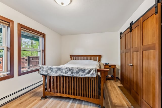 245 Tennis Ct, Silverthorne, CO 80498 - bedroom with a barn door, a baseboard radiator, and light wood-type flooring
