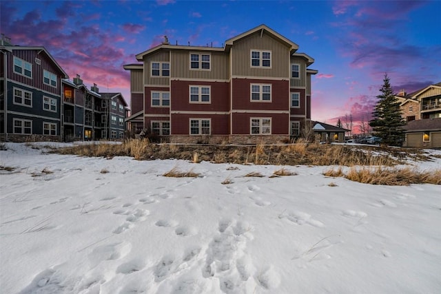 snow covered rear of property featuring board and batten siding and a residential view