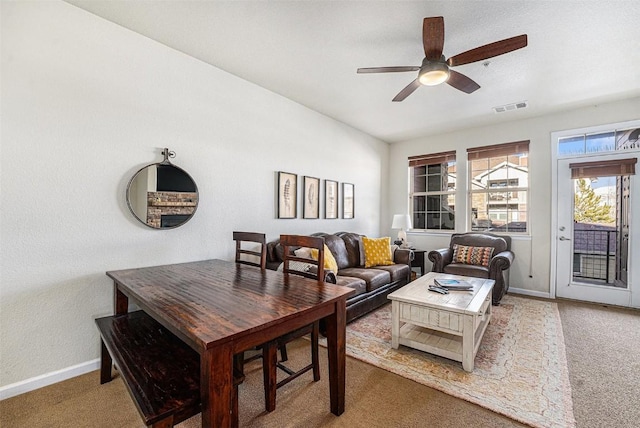 living area featuring baseboards, visible vents, carpet floors, and ceiling fan