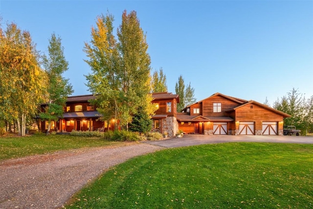 32505 County Road 20, Steamboat Springs, CO 80487 - view of front of home with asphalt driveway, a front lawn, stone siding, and a garage