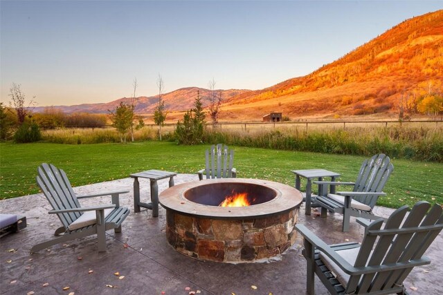 32505 County Road 20, Steamboat Springs, CO 80487 - patio terrace at dusk featuring a fire pit, a mountain view, a yard, and a patio