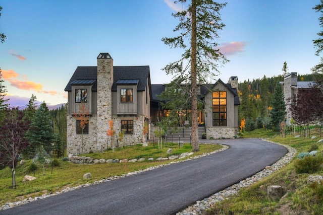257 Barton Ridge Dr, Breckenridge, CO 80424 - view of front of house with a standing seam roof, a chimney, stone siding, a metal roof, and asphalt driveway