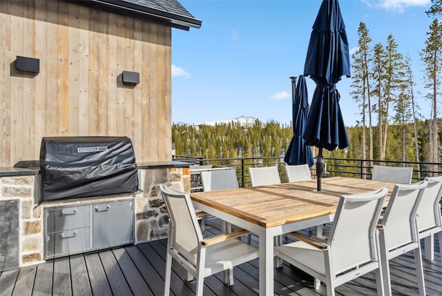 257 Barton Ridge Dr, Breckenridge, CO 80424 - deck with outdoor dining space, a view of trees, and an outdoor kitchen