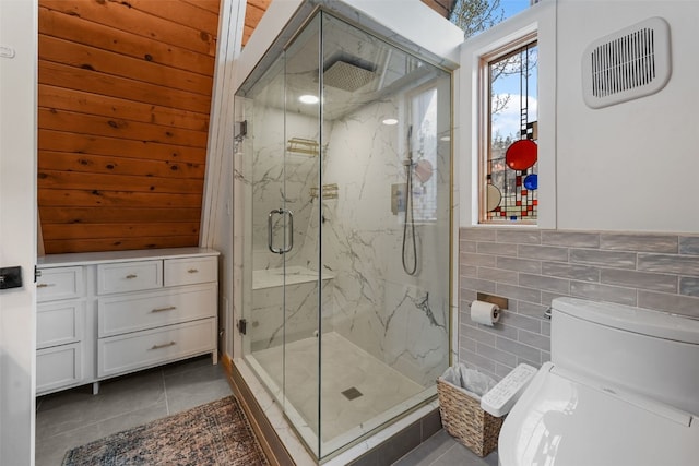 181 Shekel Ln, Breckenridge, CO 80424 - bathroom with tile patterned floors, a marble finish shower, tile walls, toilet, and wainscoting