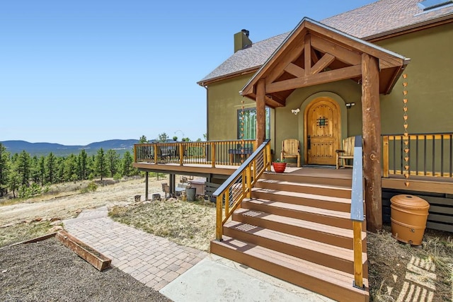 133 Lake Dr, Florissant, CO 80816 - entrance to property with stucco siding, roof with shingles, a deck with mountain view, and a chimney