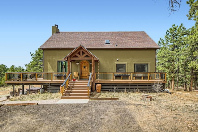 133 Lake Dr, Florissant, CO 80816 - rustic home with a chimney, a wooden deck, roof with shingles, and stucco siding