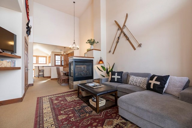 carpeted living room featuring a multi sided fireplace, high vaulted ceiling, and a notable chandelier