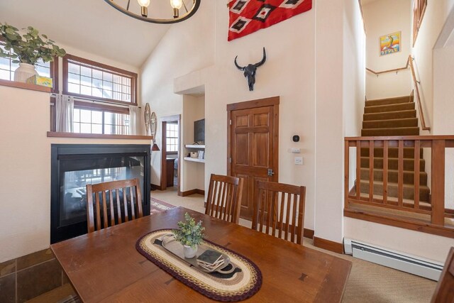 dining space with light colored carpet, baseboard heating, and high vaulted ceiling