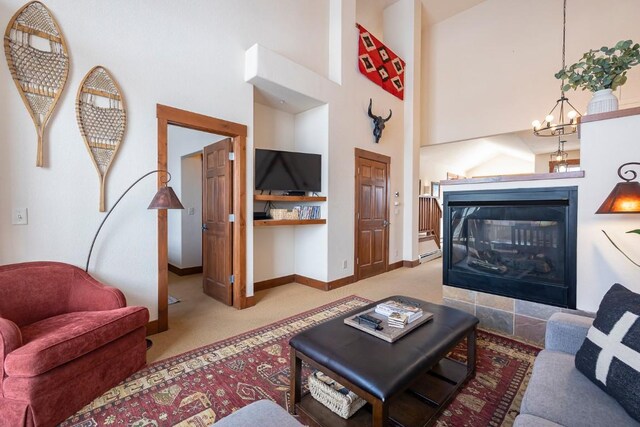 living room with a notable chandelier, a towering ceiling, light carpet, and a tile fireplace