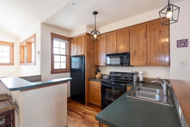 kitchen featuring pendant lighting, sink, a kitchen breakfast bar, and black appliances