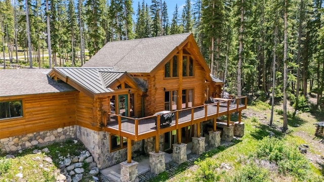 665 Whispering Pines Ln, Breckenridge, CO 80424 - rear view of house with a standing seam roof, log exterior, a wooden deck, a metal roof, and stone siding