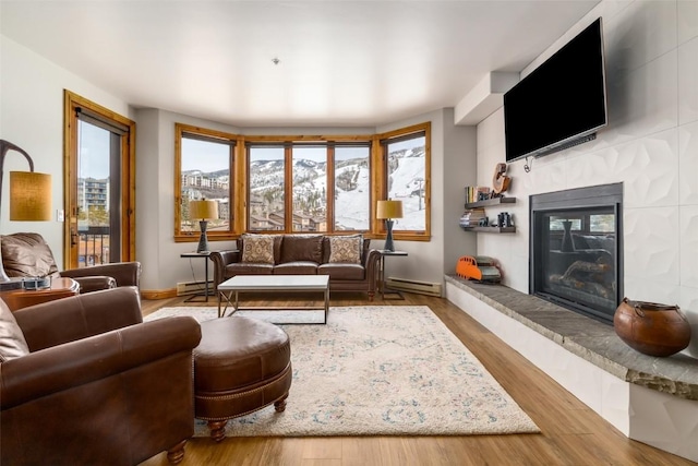 1875 Ski Time Square Dr Unit 711, Steamboat Springs, CO 80487 - living room with a baseboard heating unit, baseboards, a glass covered fireplace, and wood finished floors